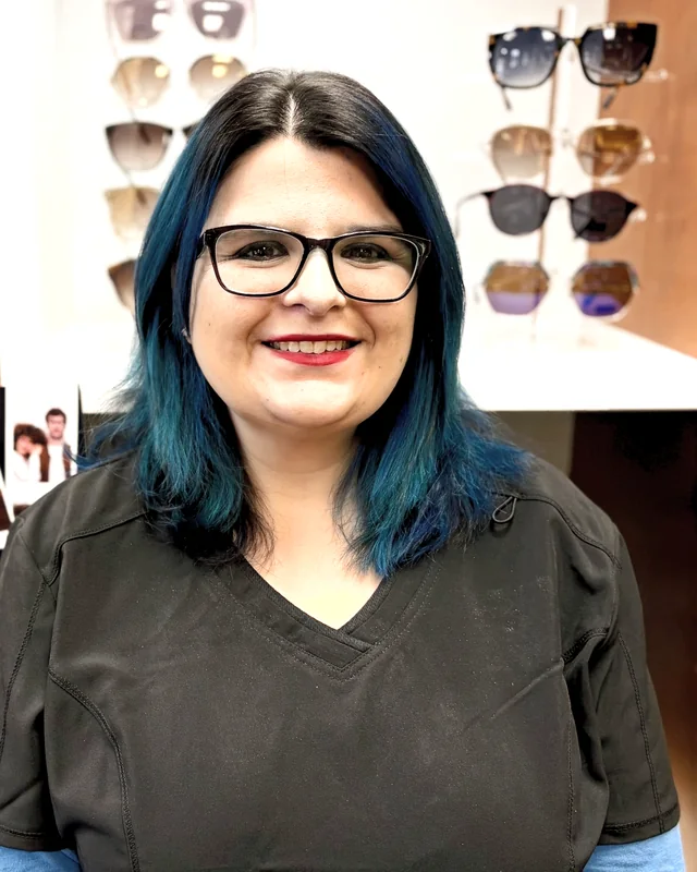 A member of the Evergreen Eye Care team in the optical, with sunglasses displayed behind.