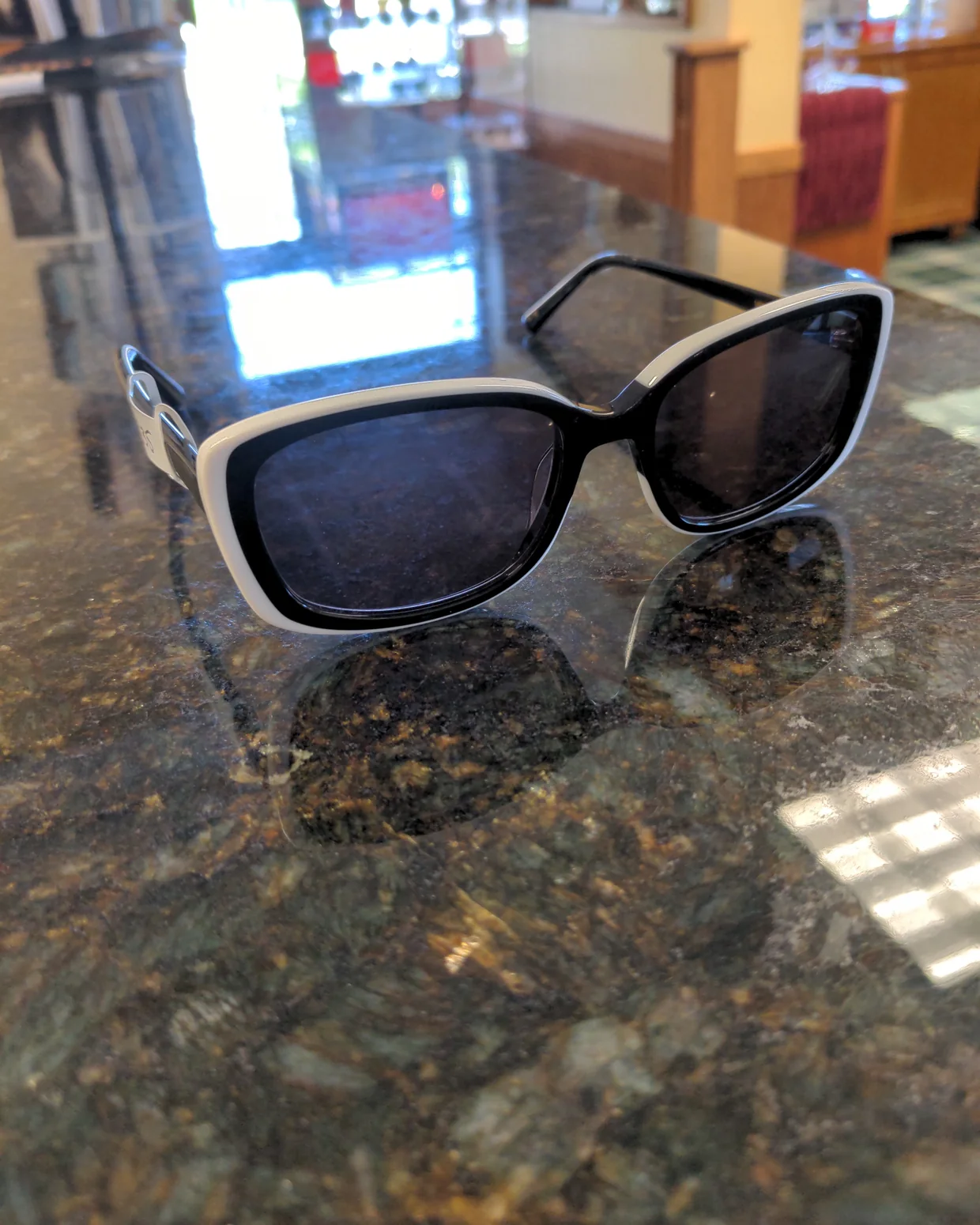 A pair of black and white sunglasses on the granite counter at Evergreen Eye Care.